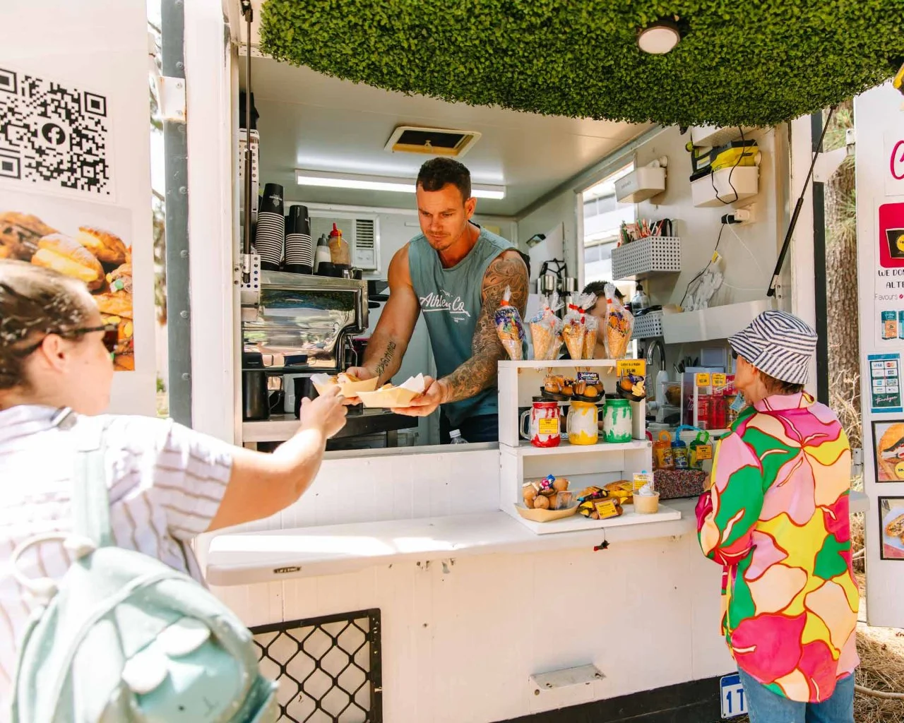 A food vendor handing takeaway food to a woman attending an event